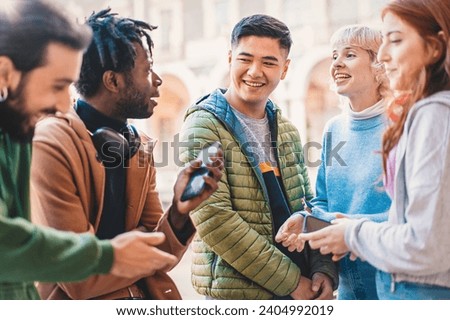 Group of diverse university students smiling and engaging with smartphones during a break in the campus courtyard.