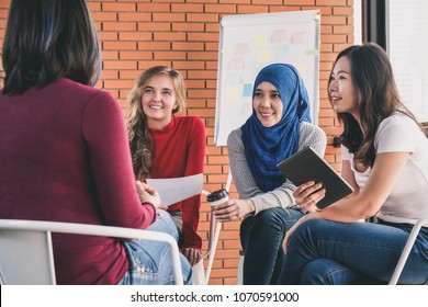 Group of diverse women in casual colorful clothes sitting in circle meeting for social project