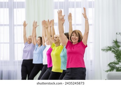 A group of diverse women of different ages are doing stretching exercises in a fitness studio. They are all wearing comfortable clothing and are barefoot. The background is a blur of light colors. - Powered by Shutterstock