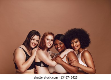 Group of diverse women with natural bodies in lingerie looking at camera with a smile. Multiracial women looking proud of their bodies.