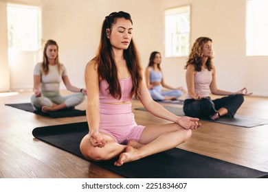 Group of diverse women practicing sukhasana meditation in a yoga class. Women of different ages doing breathing exercises in a yoga studio. Sporty women working out in a community fitness center. - Powered by Shutterstock