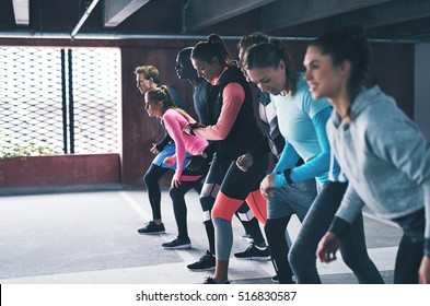 Group Of Diverse Young Friends Lining Up For A Run Inside A Large Commercial Parking Lot In A Health And Fitness Concept