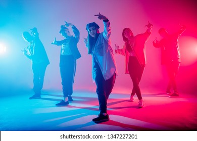 Group of diverse young hip-hop dancers in studio with special lighting effects in blue and pink colores - Powered by Shutterstock