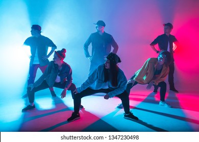 Group of diverse young hip-hop dancers in studio with special lighting effects in blue and pink colores - Powered by Shutterstock