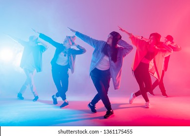 Group of diverse young hip-hop dancers in studio with special lighting effects in blue and pink colores