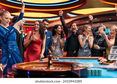 Group of Diverse Young People Gambling at a Casino. Beautiful Female and Handsome Male Guests Placing Risky Bets while Playing Roulette. Crowd Celebrating a Positive Outcome and Cheering the Winner