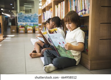 Group Of Diverse Young Students Reading Children Story Book Together