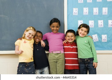 Group of diverse young students standing together in classroom. Horizontally framed shot.