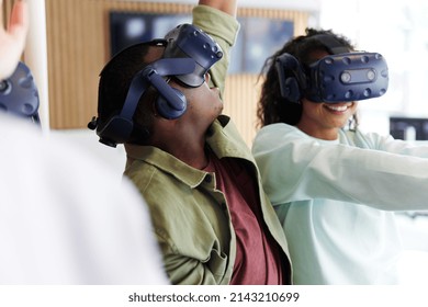 Group of diverse young teenage friends using vr headsets to explore an interactive world at a vr club - Powered by Shutterstock