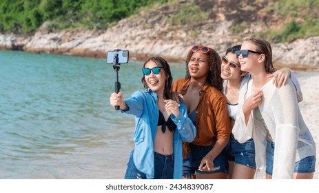 Group of diverse young women taking a selfie with a smartphone on a sunny beach day. Friends Taking Selfie at Beachside. - Powered by Shutterstock