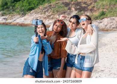 Group of diverse young women taking a selfie with a smartphone on a sunny beach day. Friends Taking Selfie at Beachside. - Powered by Shutterstock