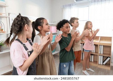 Group of diversity adorable student clapping hands at nursery school. Adorable schoolboy and girl feel happy and enjoy back to school, learning with teacher in classroom at elementary kindergarten. - Powered by Shutterstock