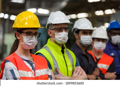 Group of diversity factory worker wearing face mask working at factory. Team of technician worker in safety uniform, helmet and face mask in the industry factory. Industry and health care concept - Shutterstock ID 1899853600