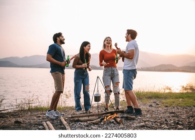 Group of diversity friends enjoy camping and dancing with a music from guitar with beautiful sunset view at the lake - Travel on vacation concept - Powered by Shutterstock