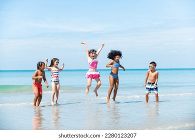 Group of Diversity little child boy and girl friends running and playing sea water at tropical beach together on summer vacation. Happy children kids enjoy and fun outdoor lifestyle on beach holiday.
