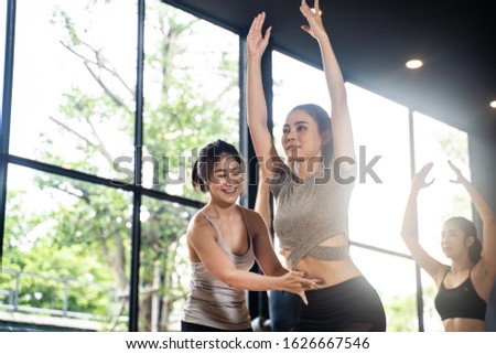 Group of diversity people training yoga in yoga class. Asian young female trainer teaching girl to standing in correct yoga pose. Fitness and yoga work out for health concept.