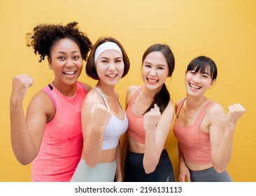 Group Of Diversity Women Of Different Race And Body Size In Sportswear Standing Together. Diverse Women With Sports Equipment Looking At Camera Against Yellow Background.