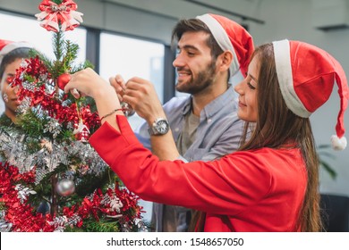 Group of diversity young creative happy celebrating Merry Christmas and Happy New Year decorating Christmas tree in office in modern office - Powered by Shutterstock