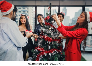 Group of diversity young happy creative worker having party celebrating New Year. Colleagues decorating Christmas tree in modern office. Merry Christmas and happy new year concept. - Powered by Shutterstock