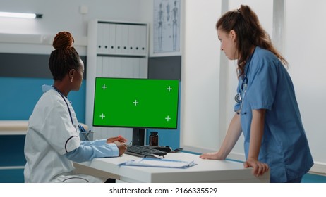 Group Of Doctor And Nurse Working With Green Screen On Monitor In Doctors Office. Medical Team Looking At Computer With Chroma Key And Mockup Isolated Template Or Background On Display.