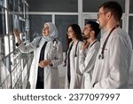 A group of doctors discusses the diagnosis of X-rays in the office. Fracture of the leg and hip joint. In the background, an Arabian professor explains to students physicians anatomy