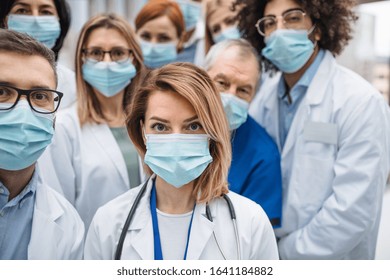 Group of doctors with face masks looking at camera, corona virus concept.