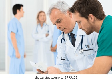 Group Of Doctors Involved In Serious Discussion With Medical Records
