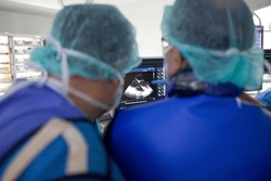 A Group Of Doctors Looking At A Picture Of A Sonogram, TAVI Transcatheter Aortic Valve Implantation, Surgery Of The Aortic Valve, A Couple Of Doctors In Scrubs Looking At A Monitor
