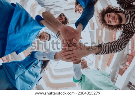 A group of doctors and a medical nurse join their hands together, showcasing the unwavering teamwork and solidarity that drives their collective efforts in the healthcare field