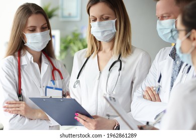 Group of doctors in medical protective masks standing with clipboards with documents in clinic - Shutterstock ID 1962861289