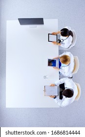 Group Of Doctors Sitting In He Office With Gadgets And Tablets In Hospital , Top View