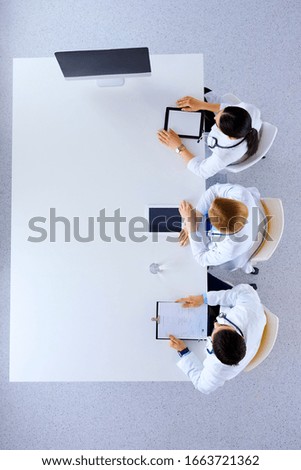 Group of doctors sitting in he office with gadgets and tablets in hospital , top view