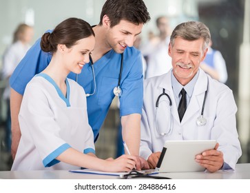 Group Of Doctors Working Together On Digital Tablet At Doctor's Office.