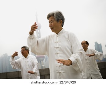 Group Doing Tai Chi Outdoors With City Skyline In Background