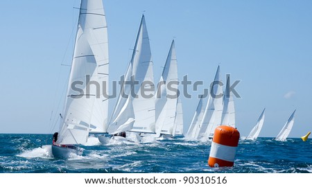 group of dragon yacht sail in regatta near a  buoy