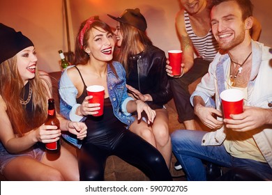 Group Of Drunk Young People Chilling At House Party, Laughing And Drinking Beer Sitting On Couch