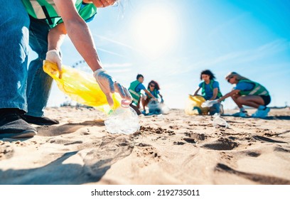 Group of eco volunteers picking up plastic trash on the beach - Activist people collecting garbage protecting the planet - Ocean pollution, environmental conservation and ecology concept - Powered by Shutterstock