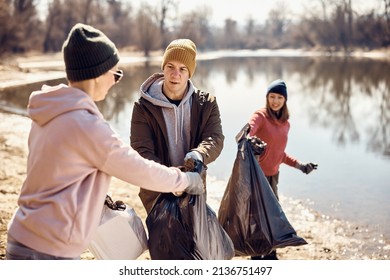 Group Of Eco-friendly People Picking Up Garage While Cleaning Beach On The Lake. 