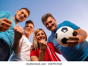 Group Of Ecstatic Fans Hugging Together , View From Bellow, Sky Background . Face Paint On, Fun Mode On!