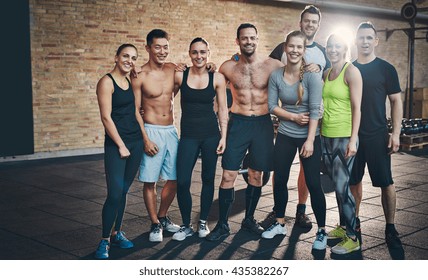 Group Of Eight Athletic Young Female And Male Adults Standing Together As Good Friends In Gym After A Difficult Workout Session