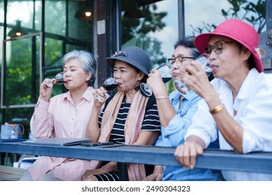 Group of elderly Asian women sitting outdoors at a restaurant, enjoying red wine. Casual clothes, relaxed setting, smiling faces, lush greenery, reflecting friendship, joy, and leisure on a bright, - Powered by Shutterstock