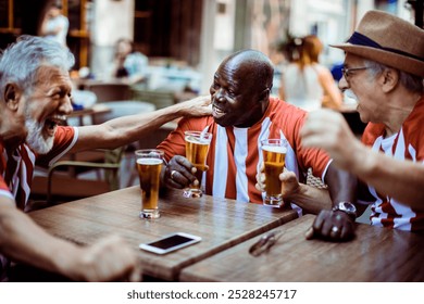 Group of elderly friends celebrating with beer after a soccer match - Powered by Shutterstock