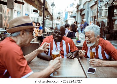 Group of elderly friends celebrating with beer after a soccer match - Powered by Shutterstock