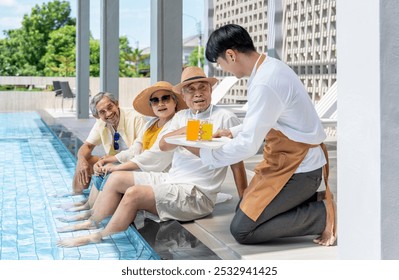 group of elderly friends talking to a waitress while serving glasses of fruit juice,asian senior with summer trip at pool side - Powered by Shutterstock