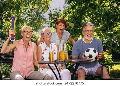 Group of elderly retired people sitting outside and watching soccer. Having beer and soccer ball. - Powered by Shutterstock