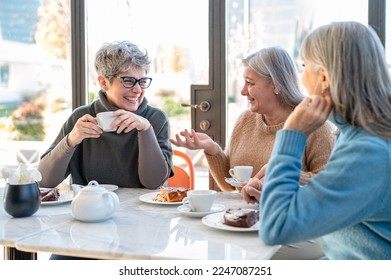 Group of elderly women having fun during breakfast in a cafeteria, three retired female friends are celebrating an anniversary, mature women drinking tea and coffee and eating cakes - Shutterstock ID 2247087251