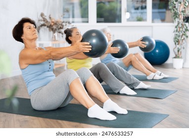 Group of elderly women practicing pilates with soft ball in fitness studio - Powered by Shutterstock