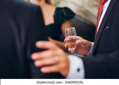 Group Of Elegant People Holding Glasses Of Champagne At Luxury Wedding Reception. People Toasting And Cheering With Drinks At Social Events.  Christmas Celebration