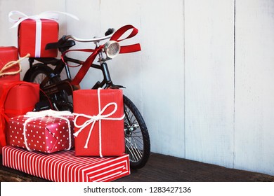 Group of elegant red gift box stack decorated with vintage toy bicycle on wood background, vibrant valentine lovely present concept, copy space