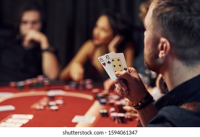 Group Of Elegant Young People That Playing Poker In Casino Together.